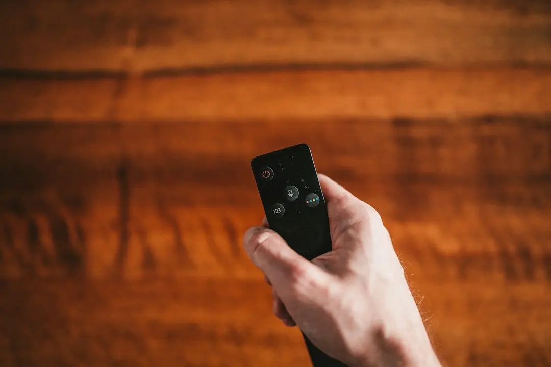 Une main tient une télécommande au-dessus d'un parquet, prête à lancer Mediaspelare sur IPTV Smarters Pro