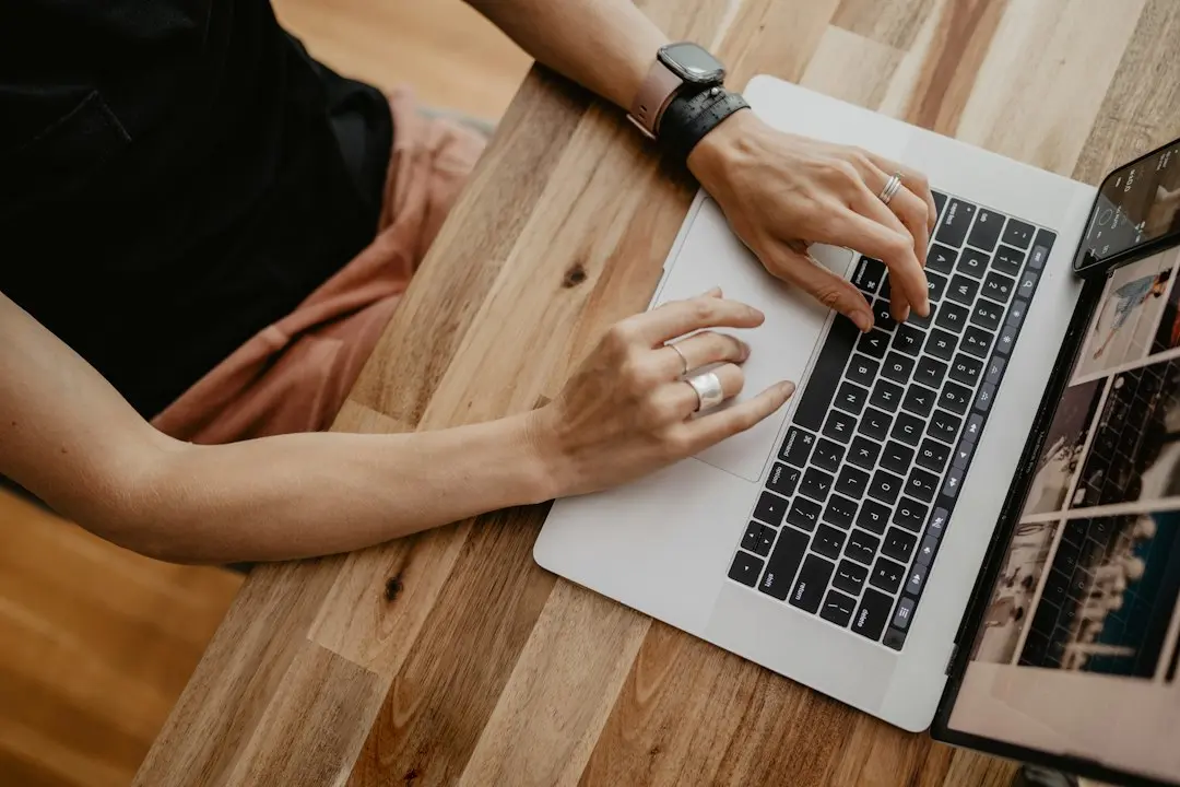 Hands typing on a laptop on a wooden desk to enter Mediaspelare login details