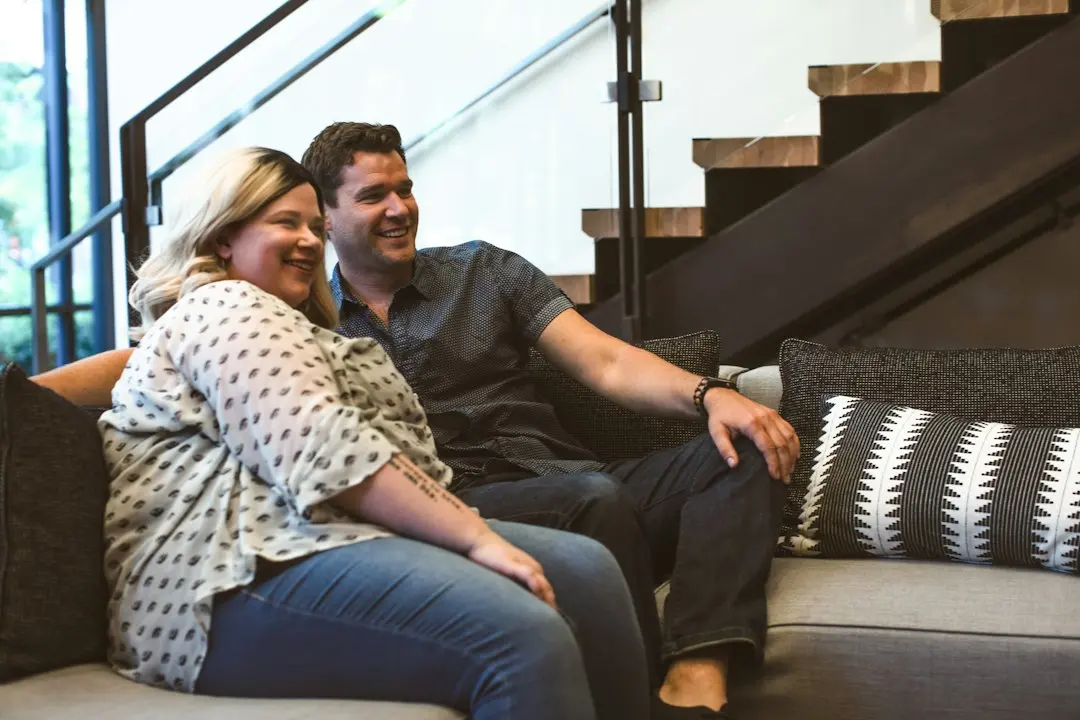 A smiling couple on a sofa in a bright living room, the kind of home Mediaspelare IPTV is for
